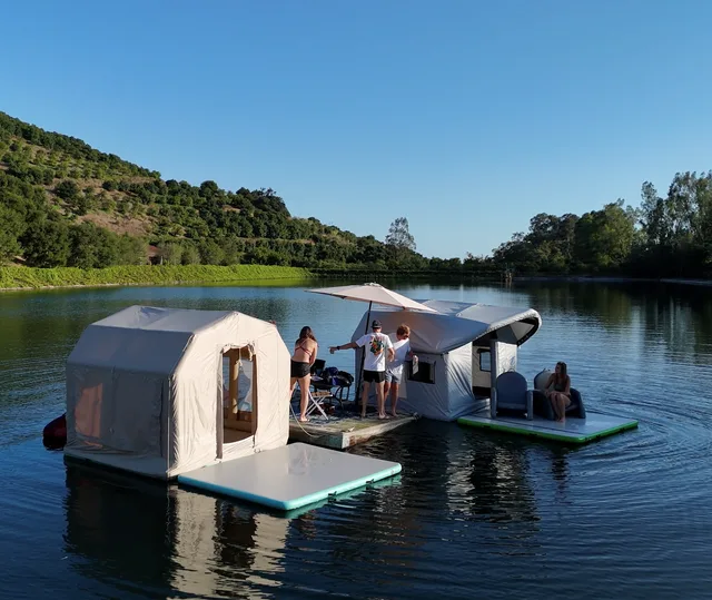 Two Transformer shelters floating on a lake with people on the platforms
