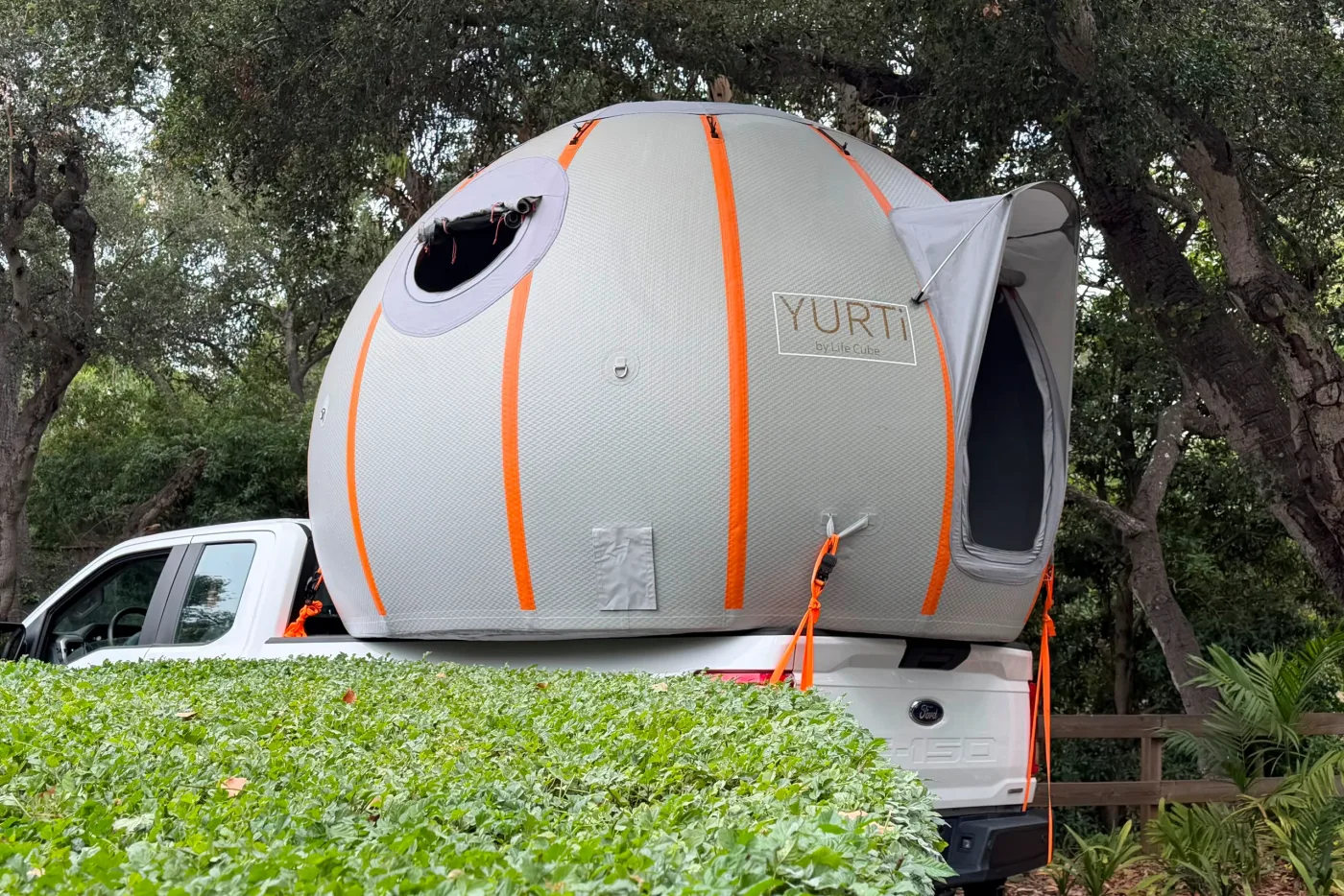Inflated YURTi loaded in the bed of a pickup truck under oak trees